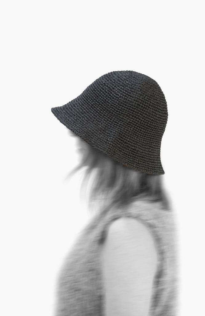 model wearing a crochet paper sun hat in charcoal colour from Karakoram Accessories viewed from the side
