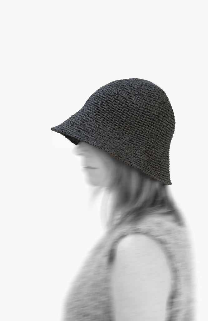 model wearing a crochet paper sun hat in charcoal colour from Karakoram Accessories viewed from the side