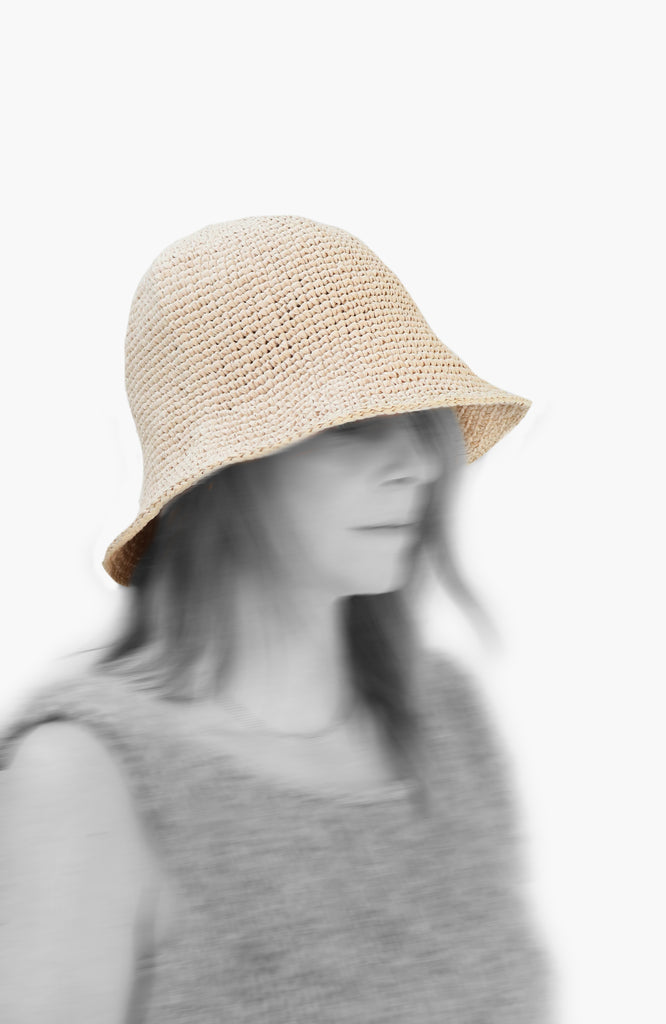 model wearing a crochet paper sun hat in ivory colour from Karakoram Accessories viewed from the side