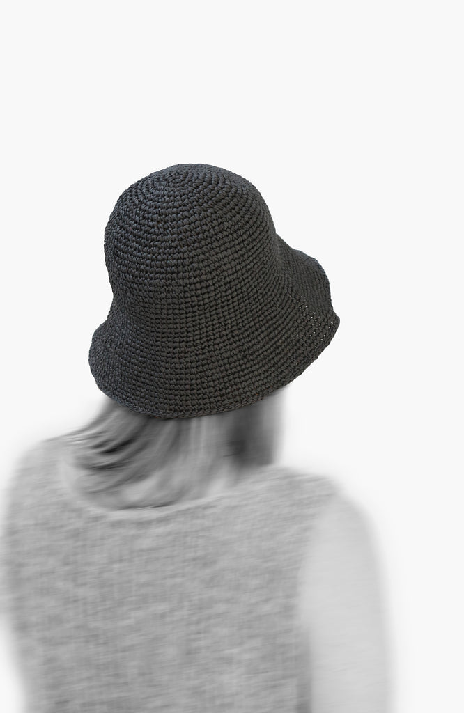 model wearing a crochet paper sun hat in charcoal colour from Karakoram Accessories viewed from the back