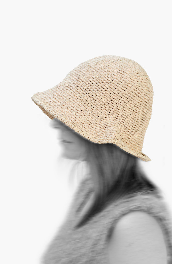 model wearing a crochet paper sun hat in ivory colour from Karakoram Accessories viewed from the side