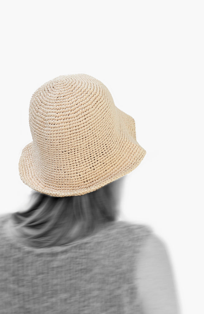 model wearing a crochet paper sun hat in ivory colour from Karakoram Accessories viewed from the back