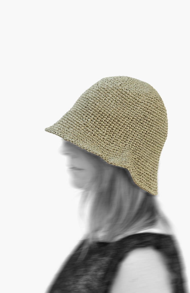model wearing a crochet paper sun hat in tarragon colour from Karakoram Accessories viewed from the side
