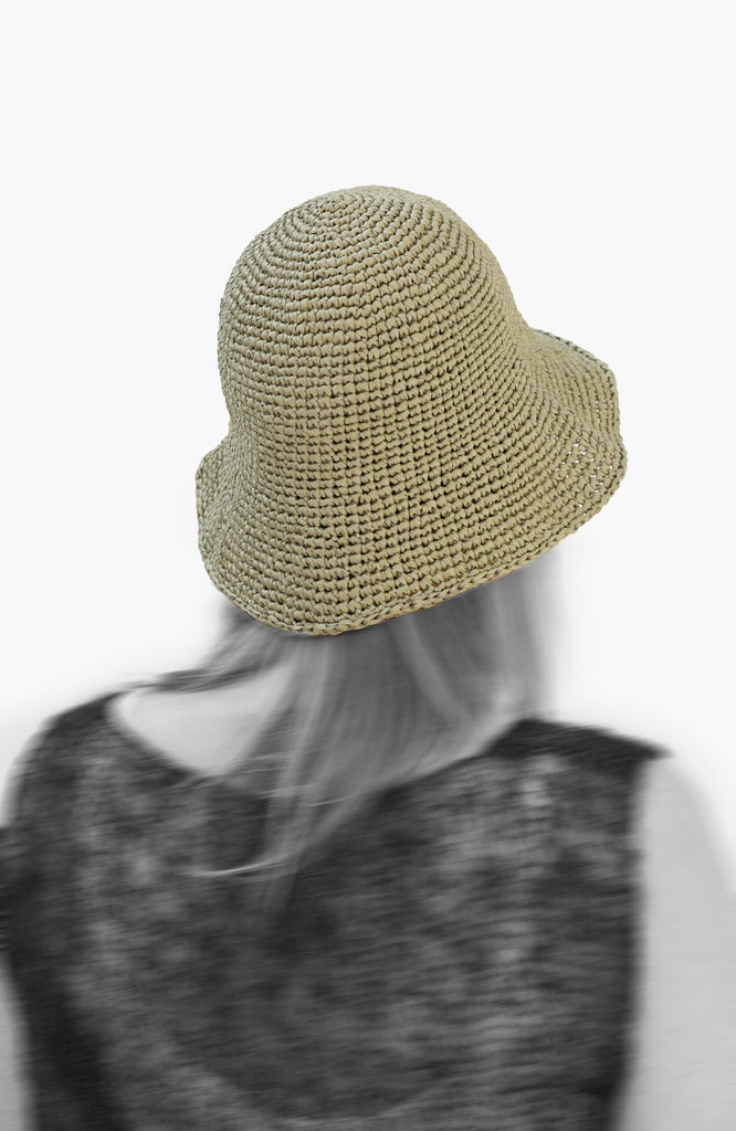model wearing a crochet paper sun hat in tarragon colour from Karakoram Accessories viewed from the back