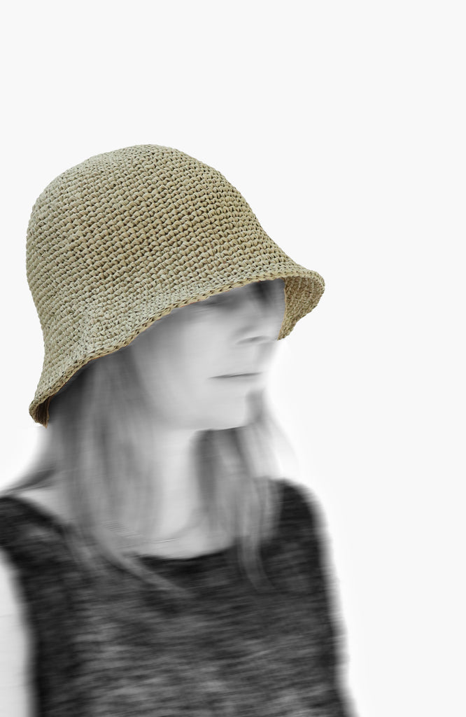 model wearing a crochet paper sun hat in tarragon colour from Karakoram Accessories viewed from the side